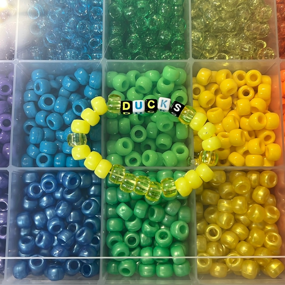 A Kandi rave bracelet that says, “Ducks”